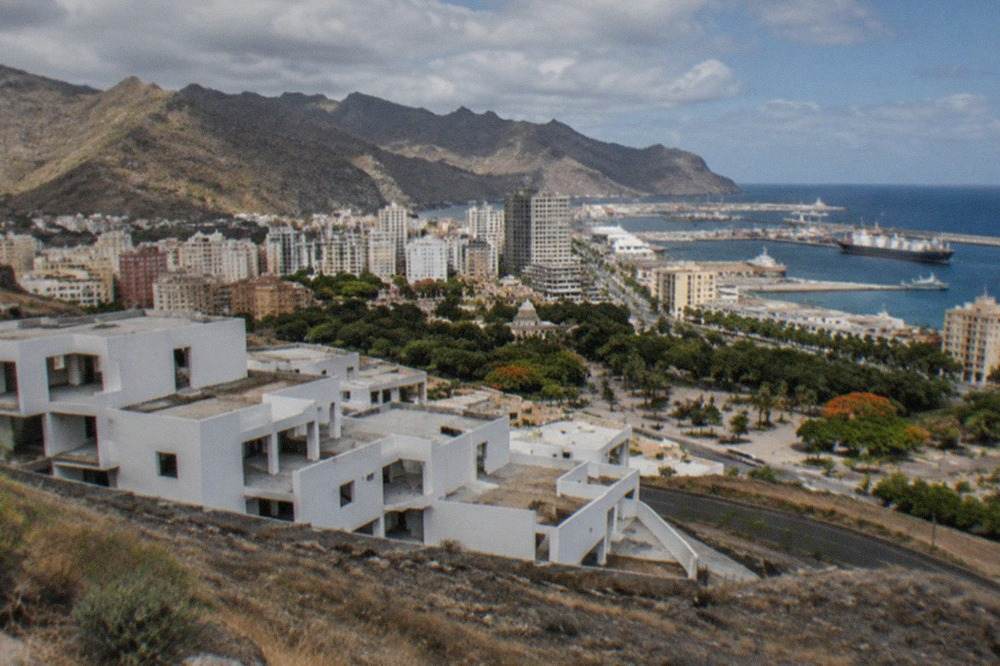 Empty white buildings of an unfinished complex standing on open ground near the coast