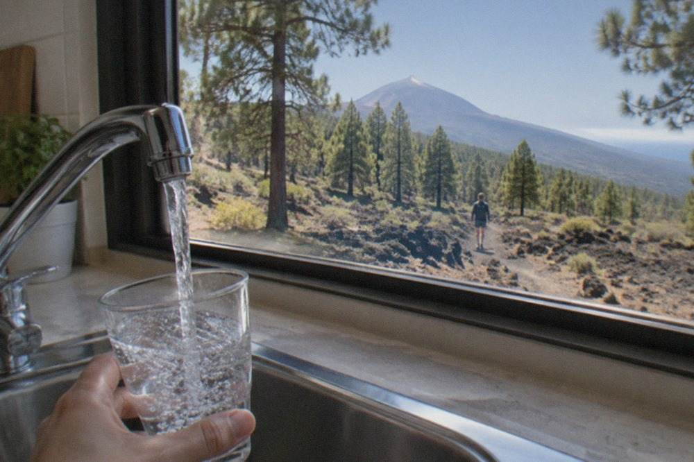 A glass of water being filled from a kitchen tap in a bright holiday apartment