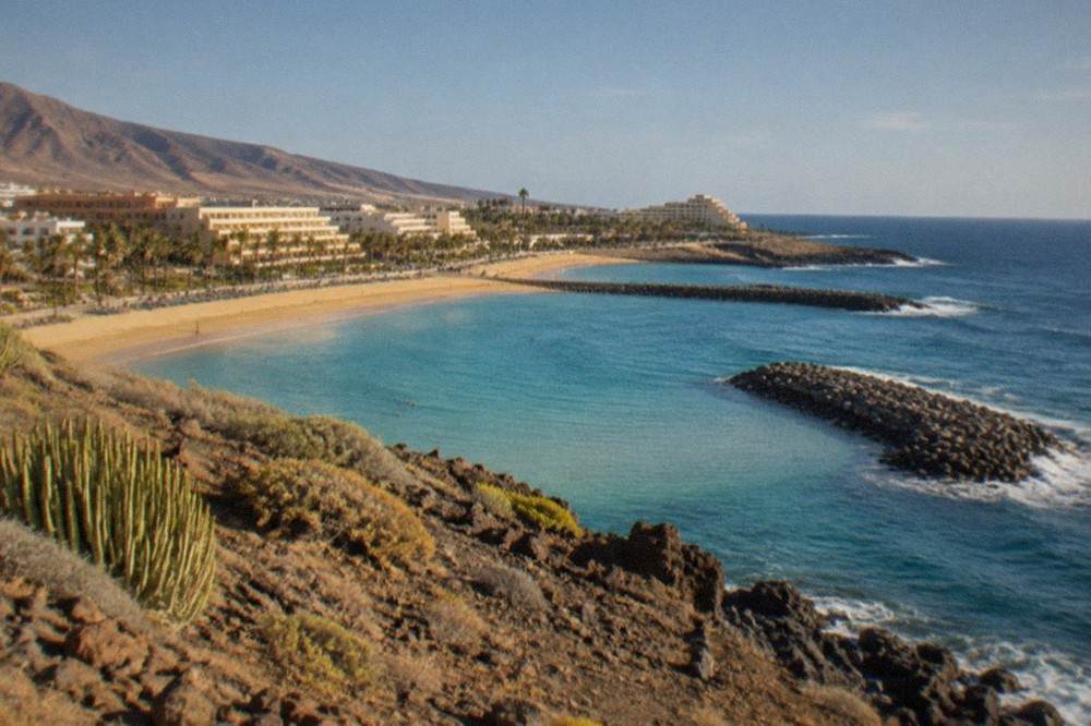 A sheltered Tenerife bay with breakwaters and calm turquoise water along the shore