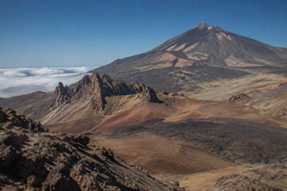 View over the volcanic slopes of Mount Teide rising above the clouds in Tenerife