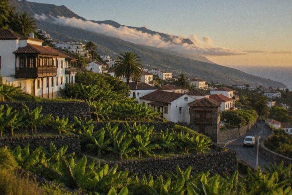 A view across a Tenerife resort coastline towards green hills under a clear sky