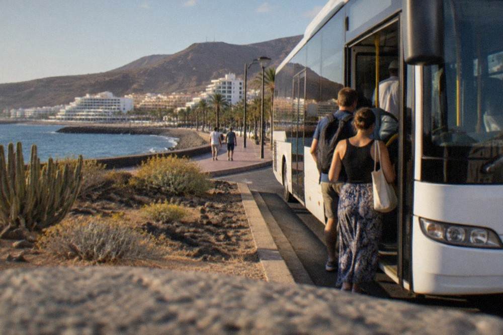 A Tenerife bus stopping at a coastal resort stop with passengers boarding