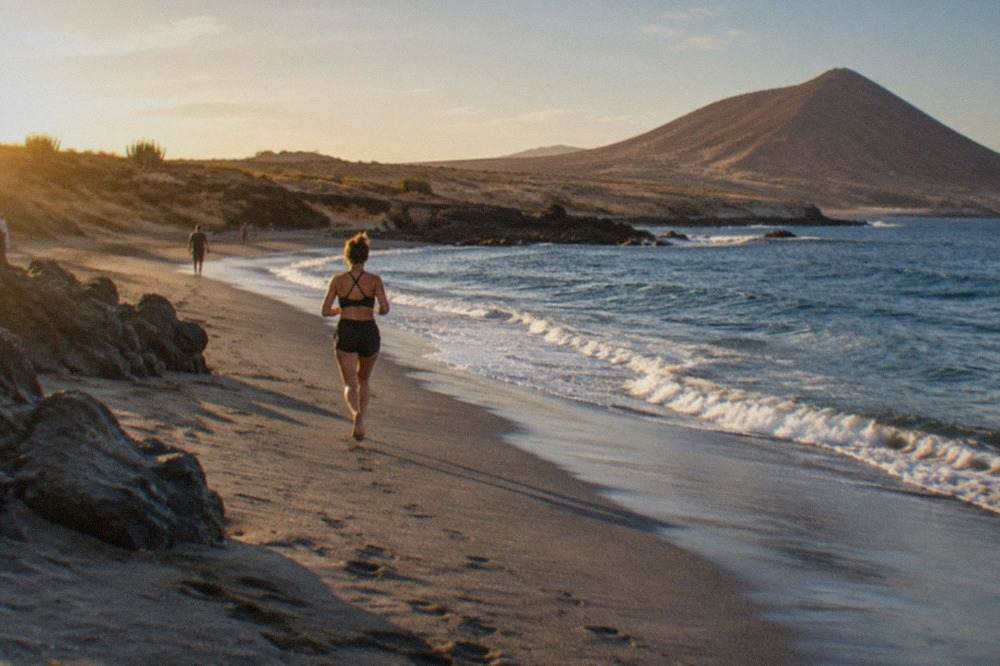 A calm swimming bay on the Tenerife coast with dark volcanic sand and clear blue water