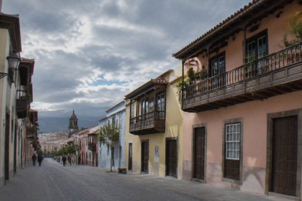 Pastel-coloured colonial buildings with wooden balconies lining a quiet town street in La Laguna