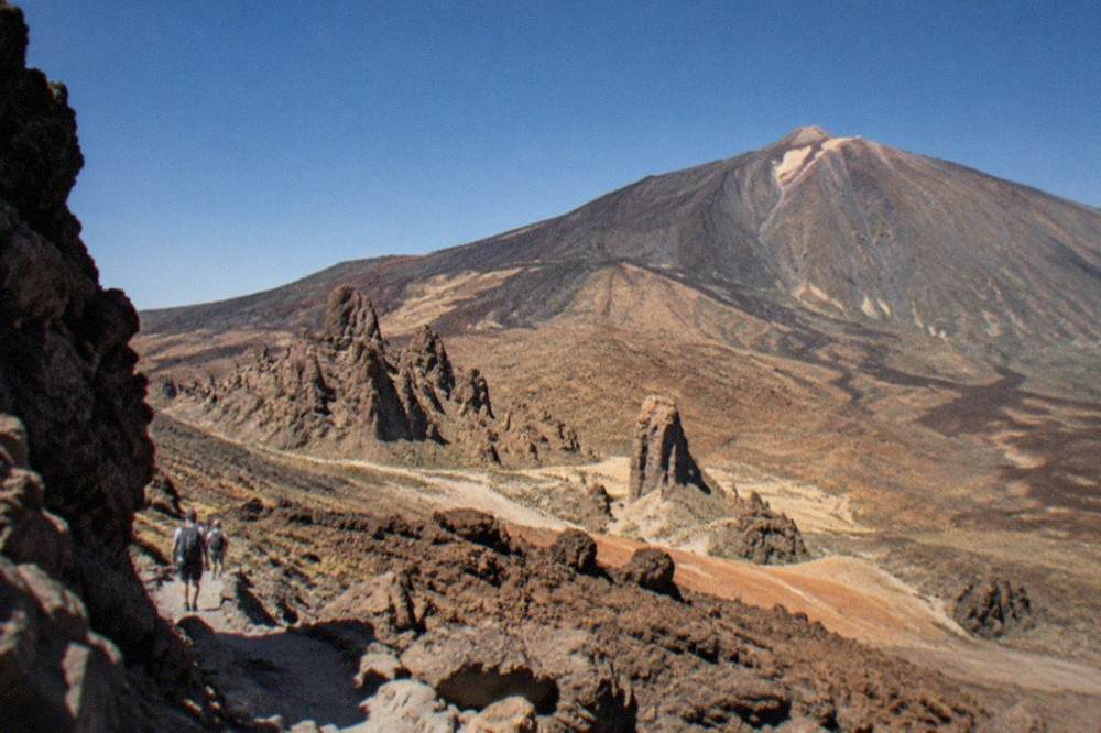 Dark volcanic rock formations on the upper slopes of Teide National Park under a clear sky