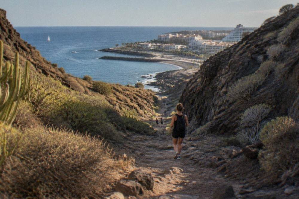 A rocky ravine path descending towards the sea between high cliffs