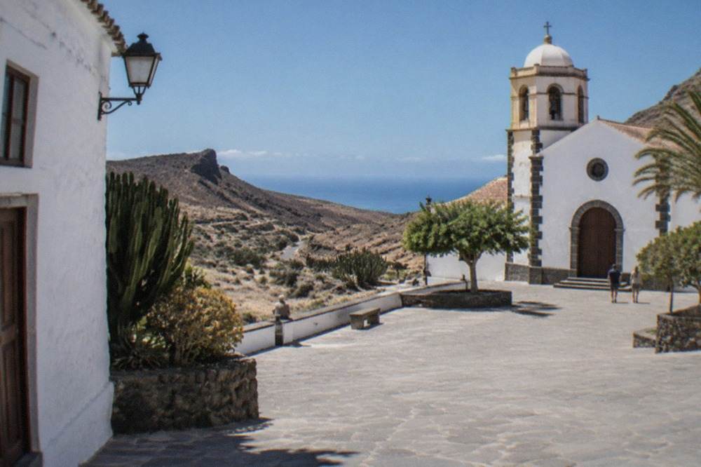 Whitewashed Canarian houses and a church square in Adeje old town under a bright sky