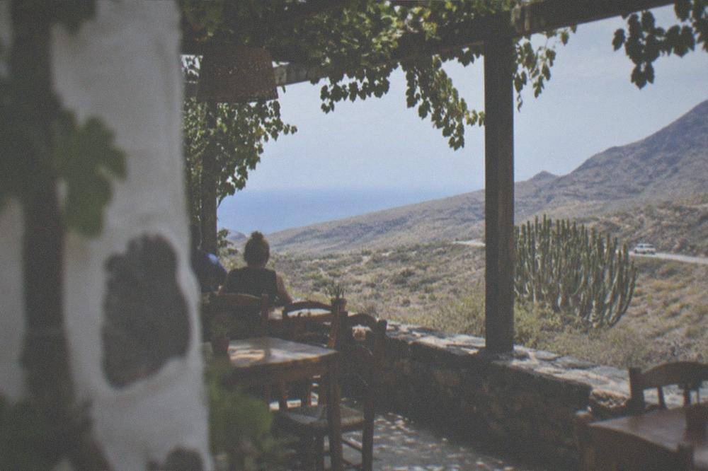 A small Canarian restaurant terrace with wooden tables and shaded vines in Adeje