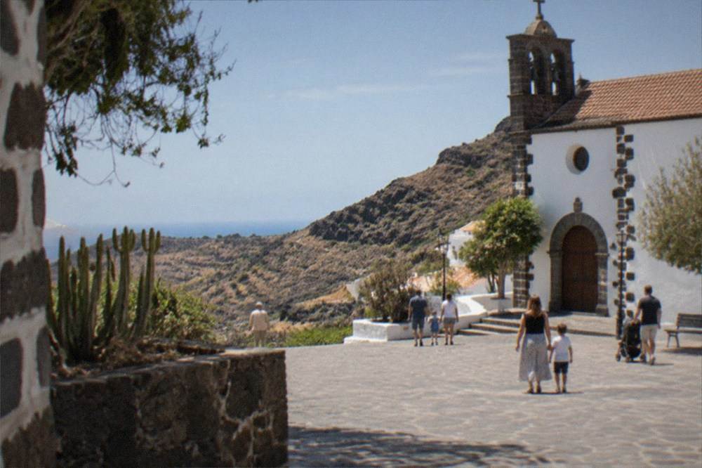 Families walking through a sunny church square in a Canarian old town