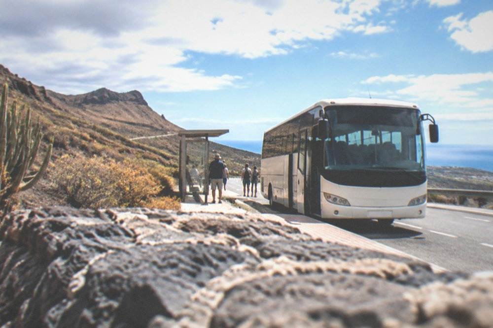 A bus at a coastal stop on a sunny road in Tenerife