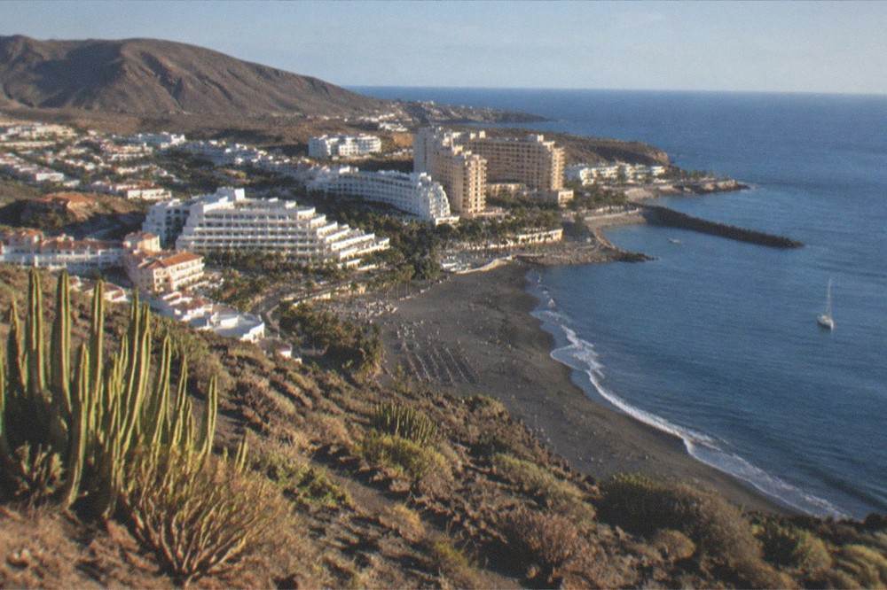 Aerial view of a resort coastline with hotels and a sandy beach in Tenerife