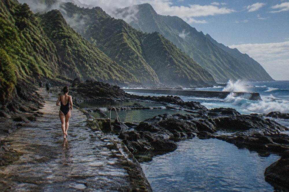 Natural rock pools on a volcanic coastline with waves breaking against the seawall