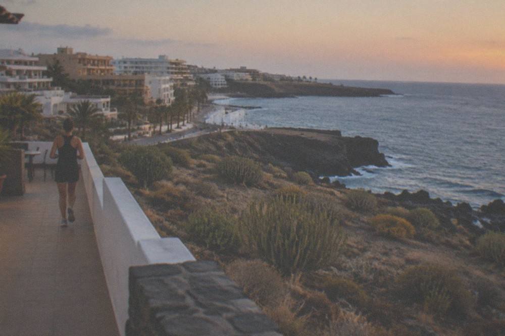 A quiet evening terrace overlooking the sea with a few lit windows in low buildings