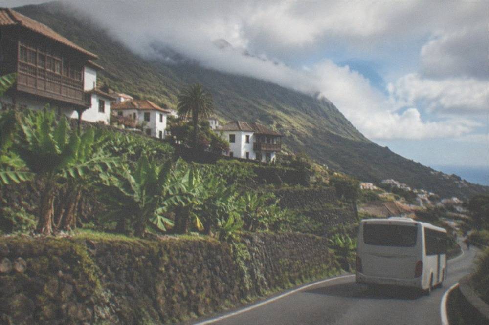 An island bus on a road through green hills in northern Tenerife