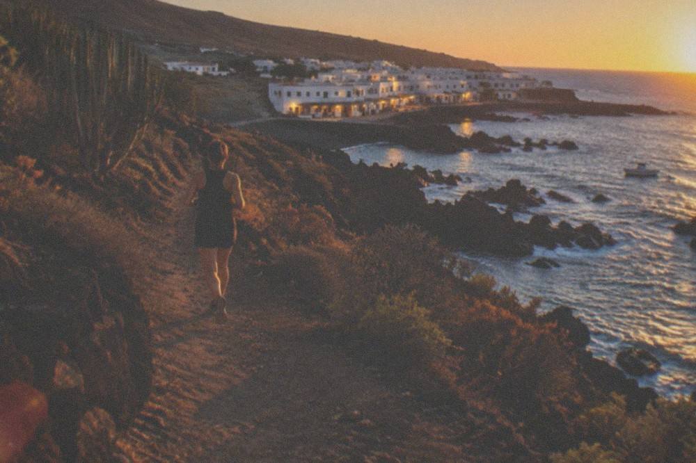Low white village buildings above the sea at dusk with lights reflecting on the water