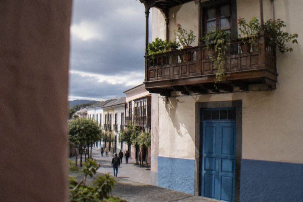 A wooden balcony above a blue-painted doorway on a colonial house in La Laguna