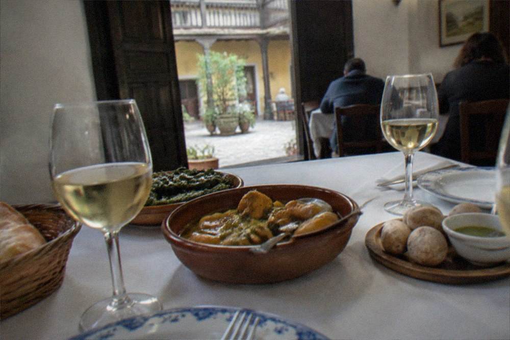 A table set with wine glasses and Canarian dishes in a small eating room