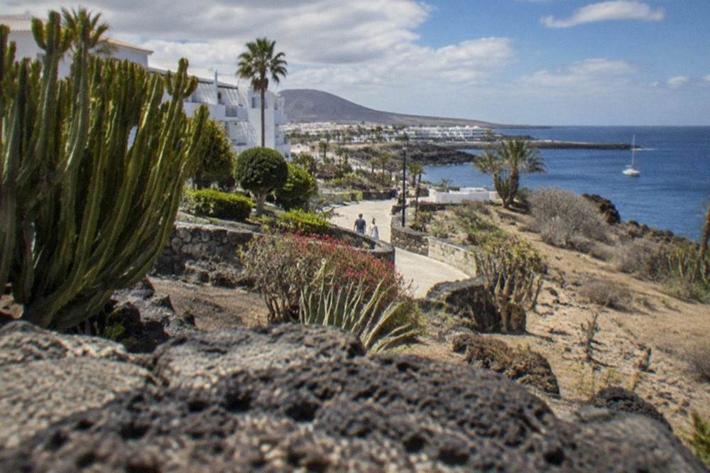 A low-rise holiday resort of white apartment buildings surrounded by gardens near the sea