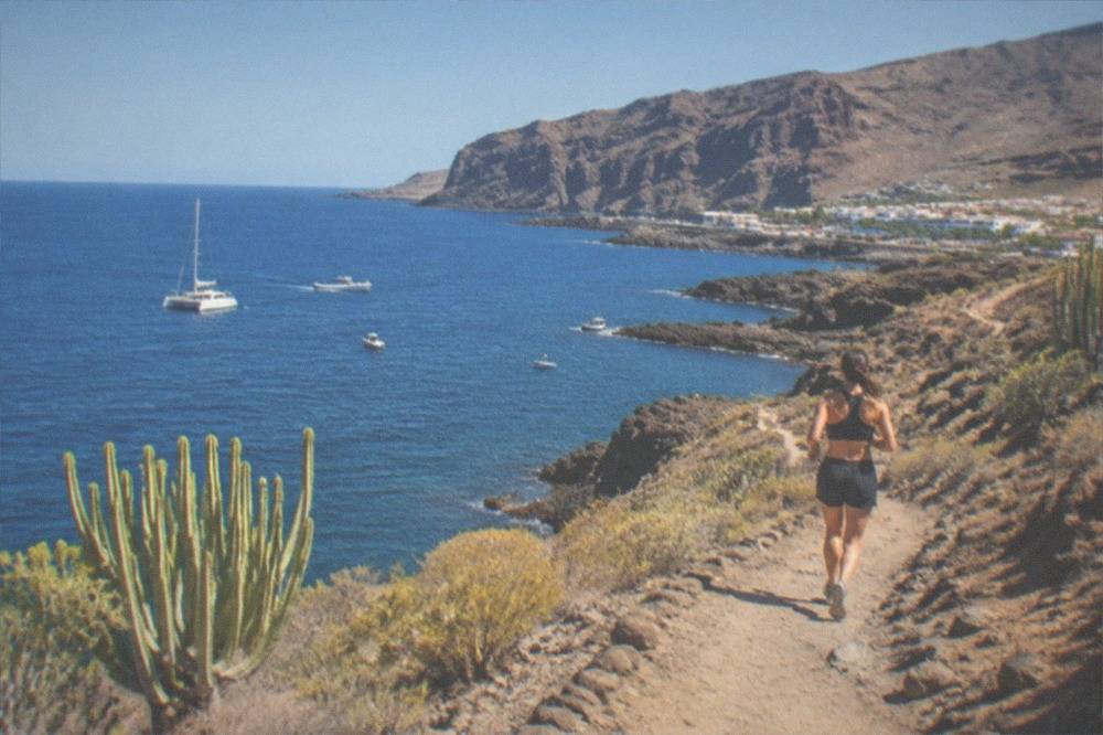 A catamaran and small boats on blue water near the cliffs of southern Tenerife