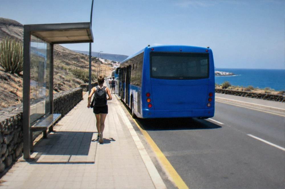 A blue island bus at a stop on a coastal road in southern Tenerife