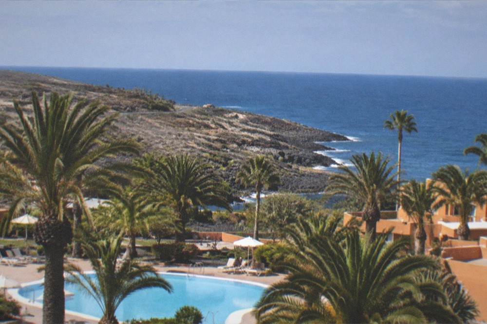An apartment complex with palm gardens and a swimming pool near the sea