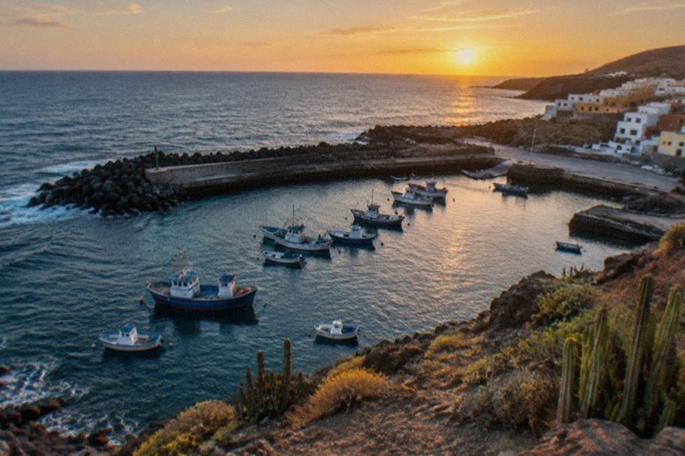 Fishing boats moored in a small harbour with calm water and an evening sky
