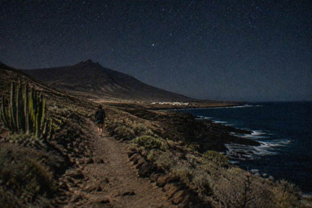 A night sky full of stars above a dark volcanic silhouette