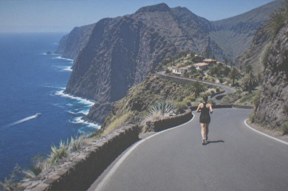 A winding mountain road with cliffs and the sea in the distance on a clear day