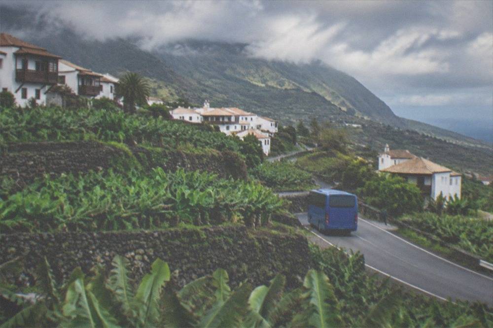 Blue island bus on a road between green fields in northern Tenerife