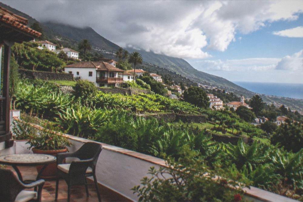 Small hotel terrace overlooking gardens and the sea on a green hillside