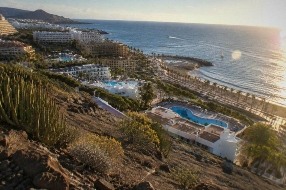 Aerial view of hotel rooftops and pools along a south Tenerife coastline