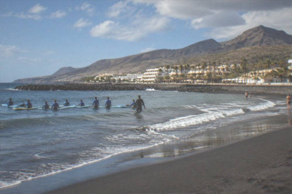 Gentle rolling waves on a sheltered resort beach with a surf school group in the shallows