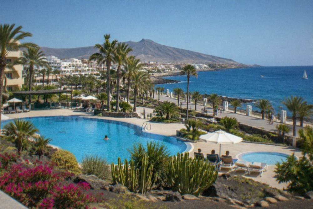 Hotel pools and palm gardens in a resort complex under a clear morning sky