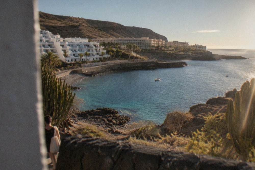 White apartment buildings above a small rocky bay with calm turquoise water
