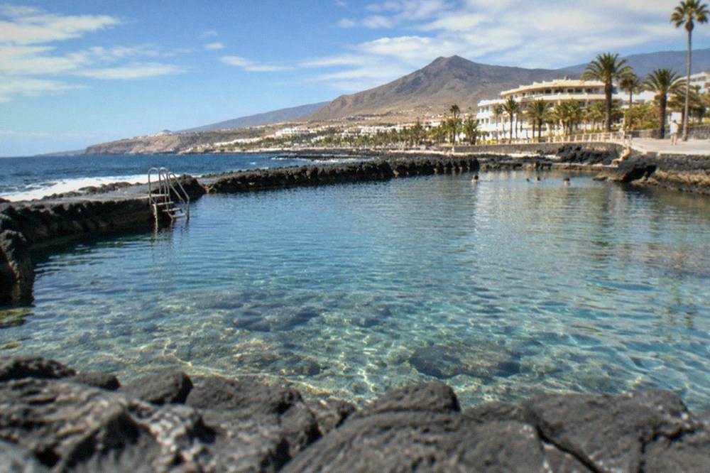 A sheltered sea pool between stone breakwaters with clear water and a sunny sky