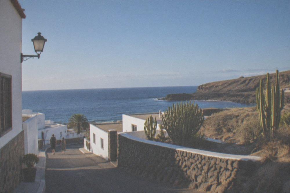 A quiet seaside village street with white buildings and an ocean view in Tenerife