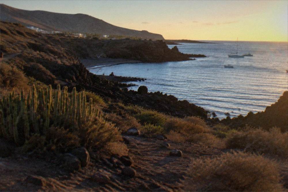 Sunshine over a calm bay with dark rock formations along the shoreline