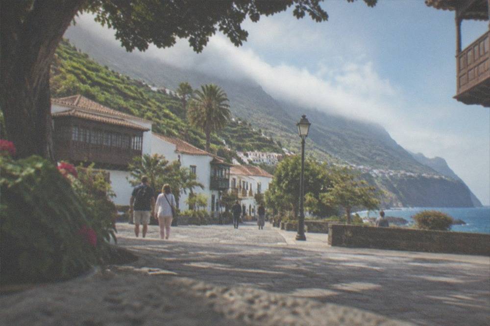 Visitors strolling a shaded plaza in the old quarter of Puerto de la Cruz