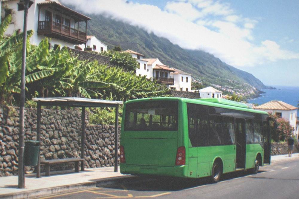 A green island bus at a stop in a Tenerife town