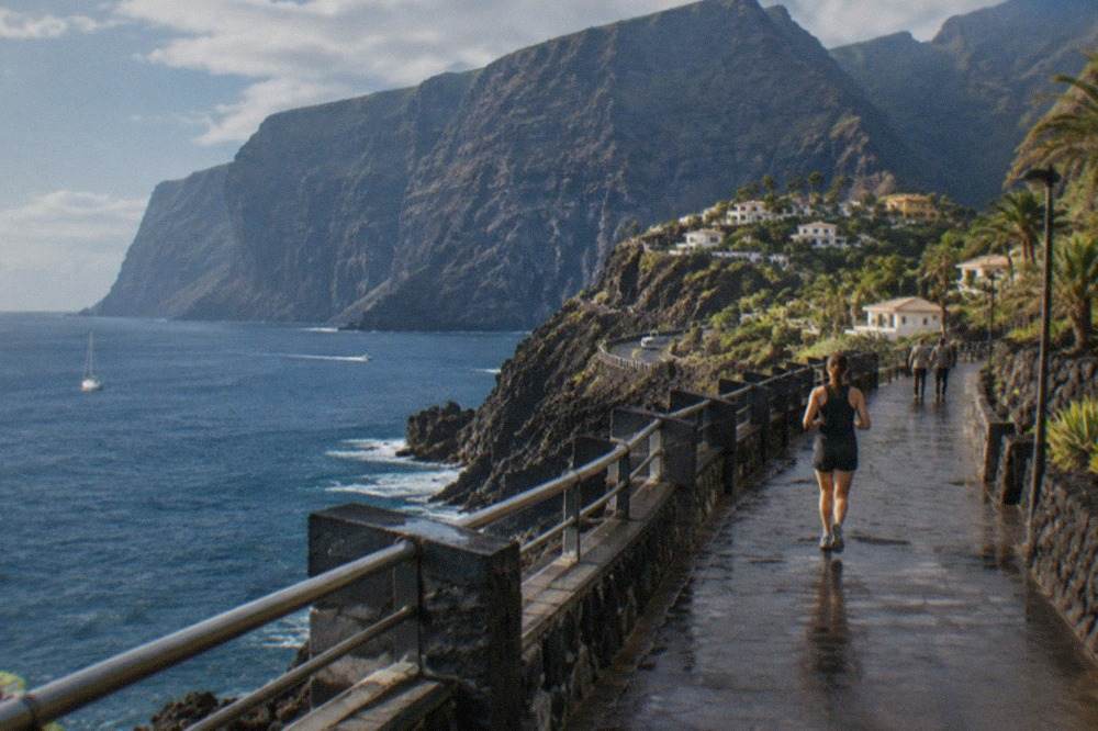 A coastal promenade in west Tenerife with dark volcanic rock and the ocean beyond