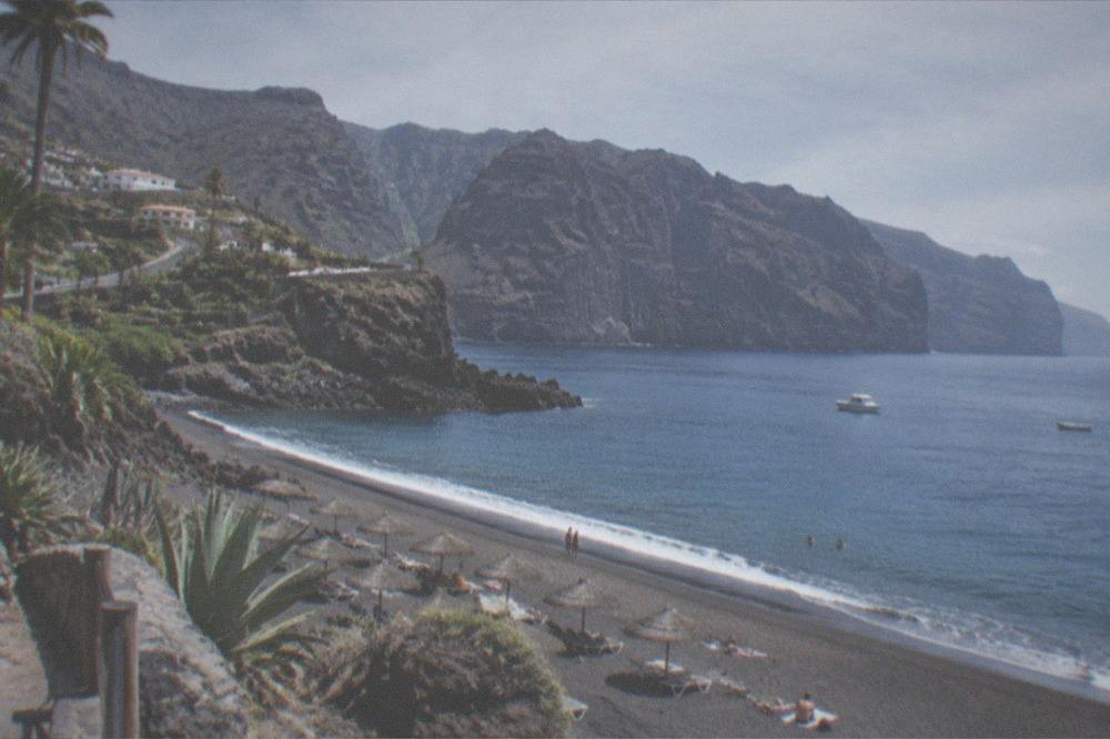 A sunny beach on the west coast with calm water and parasols