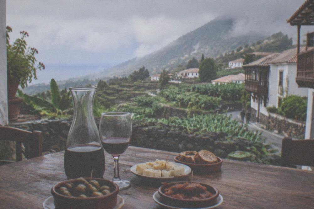 A rustic Canarian country kitchen table with small plates and a carafe of red wine