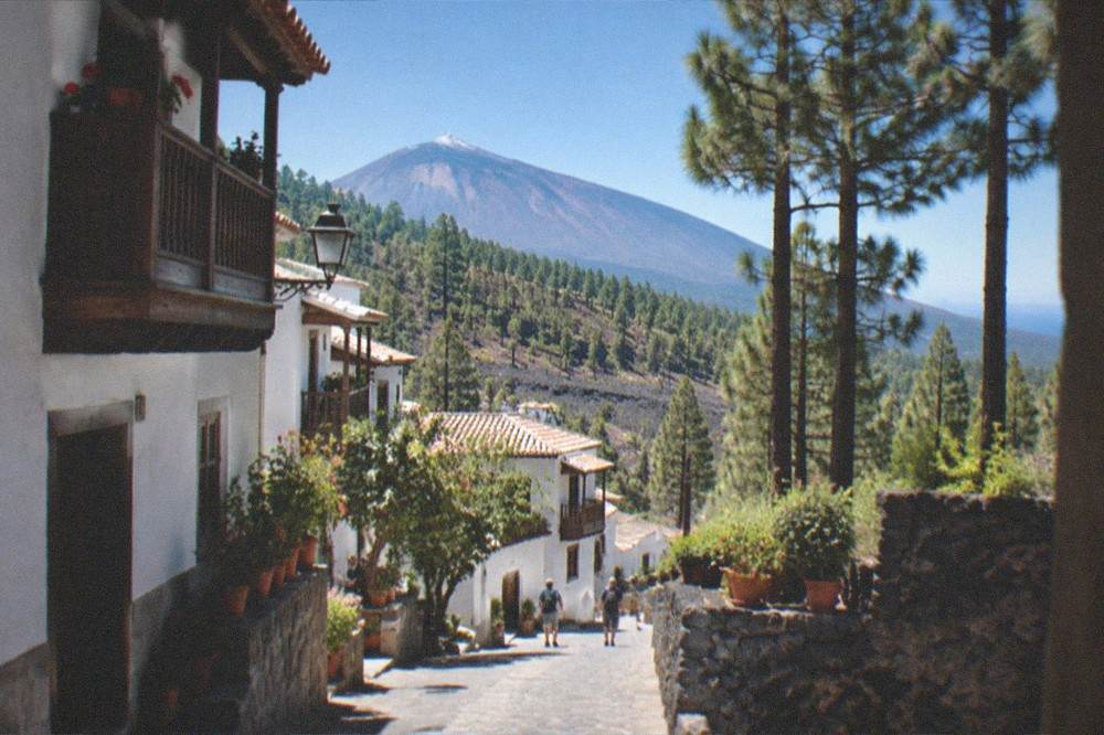 A quiet village street with white-walled houses, wooden balconies and potted plants