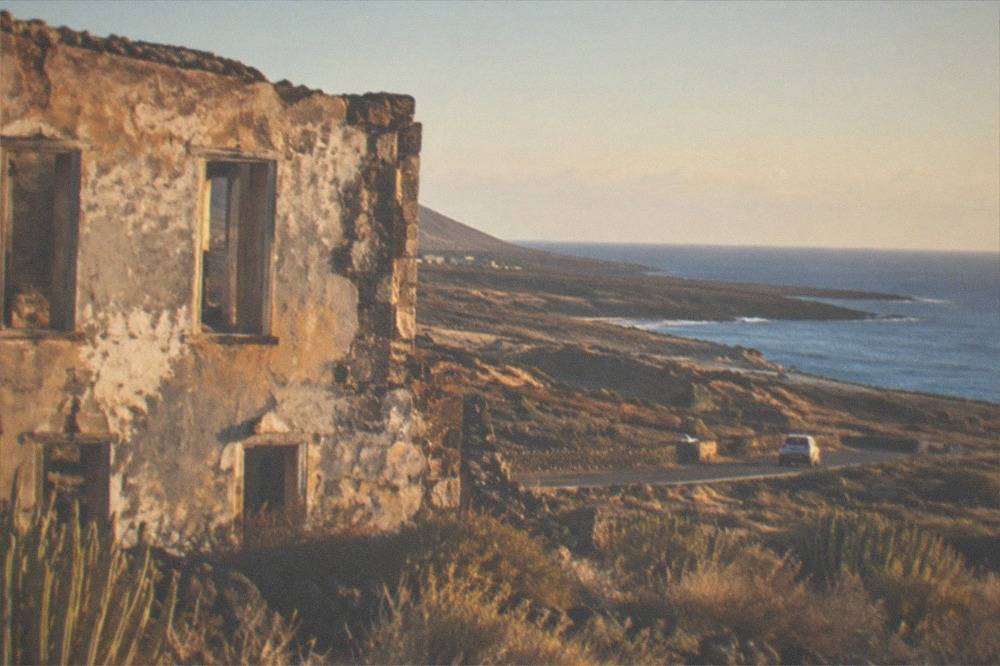 A weathered abandoned building facade with empty window openings and faded paint