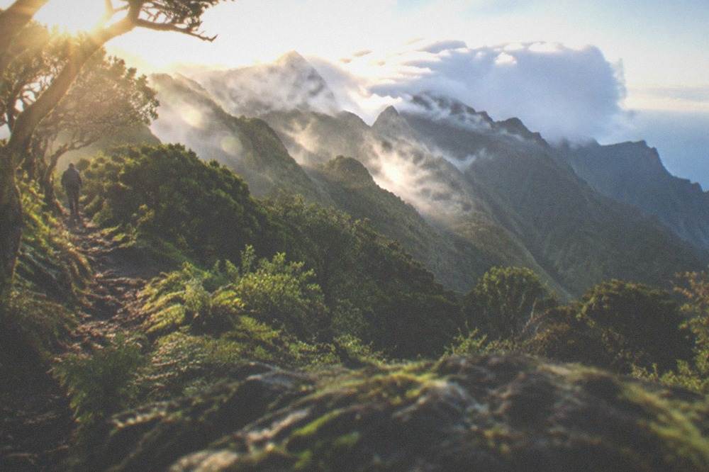 Cloud rolling over a green ridge line above the sea in northeast Tenerife