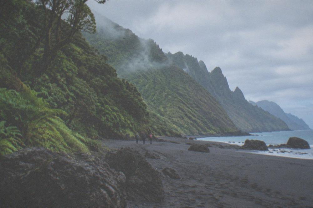 A dark volcanic sand beach at the foot of green cliffs on the Anaga coast