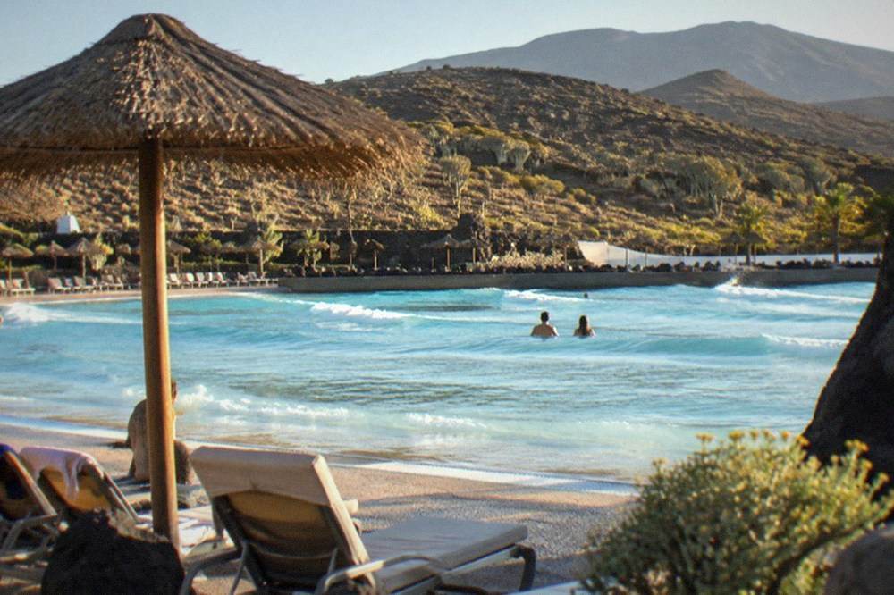 A wide wave pool with sun loungers and parasols along the edge