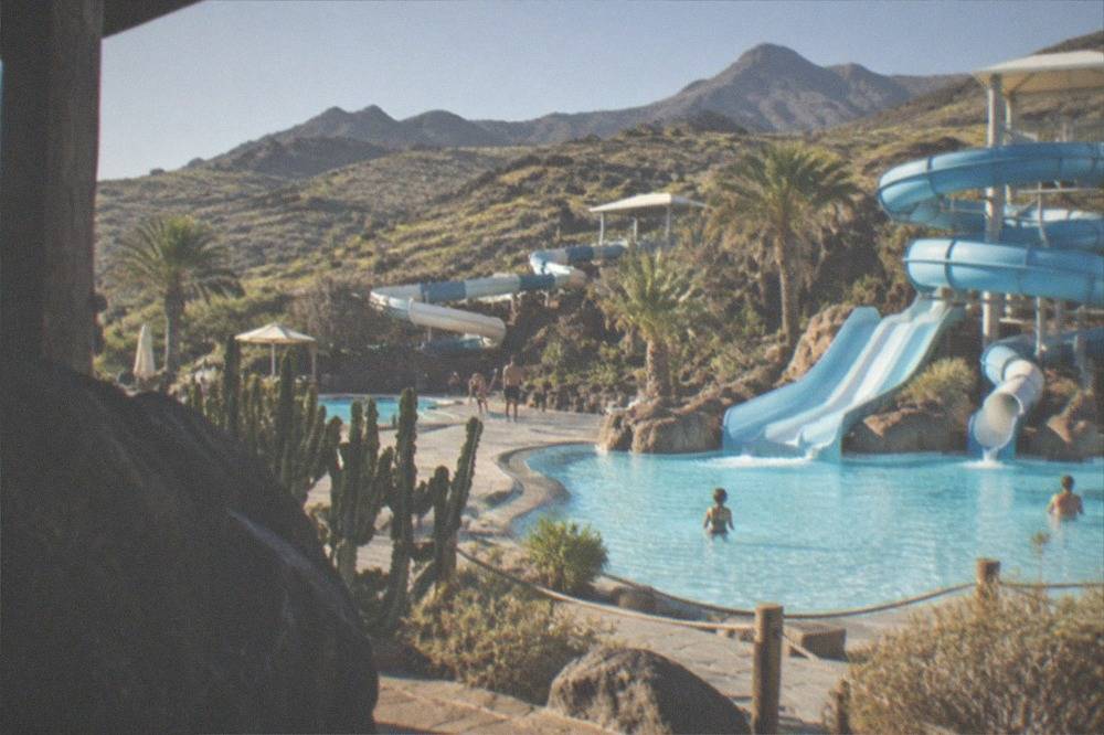 Pale blue pools and water slides at an outdoor water park under a bright sky