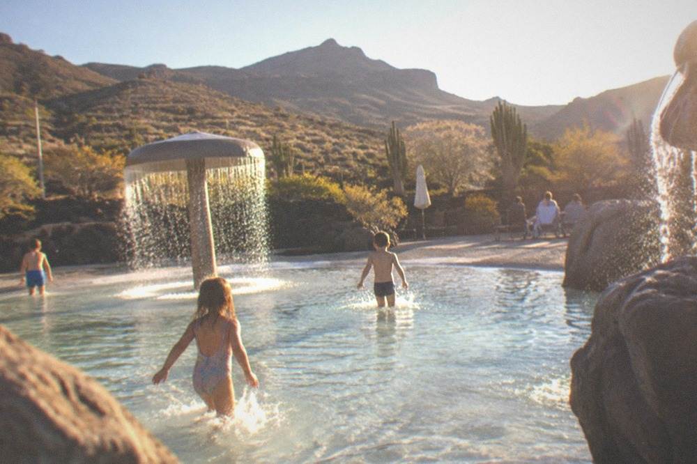 Children splashing in a shallow pool with small water features