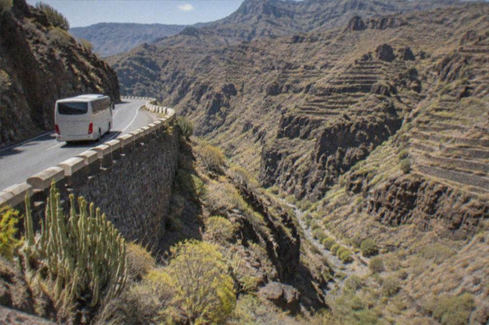 A coach on a mountain road above terraced hillsides in central Tenerife